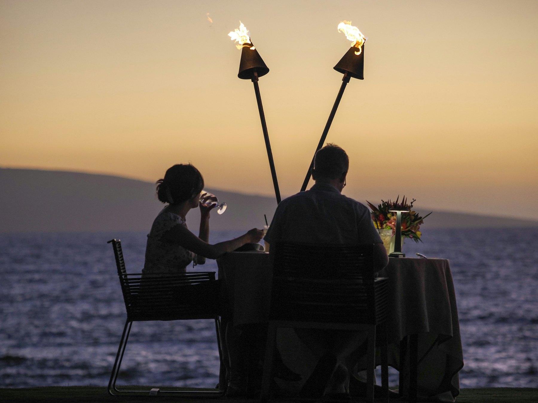 Una coppia a cena in riva all'acqua al tramonto